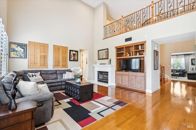 428 Lloyd Ct, Benicia, CA 94510 - living area featuring wood finished floors, a high ceiling, a glass covered fireplace, baseboards, and built in shelves