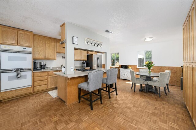 103 Quail Ct, Winters, CA 95694 - kitchen featuring double oven, a textured ceiling, light countertops, freestanding refrigerator, and a kitchen bar