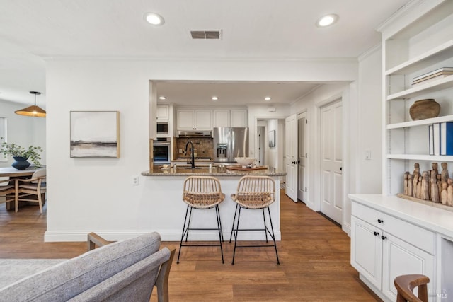16 Tradewind Psge, Corte Madera, CA 94925 - kitchen featuring appliances with stainless steel finishes, under cabinet range hood, a peninsula, white cabinetry, and a breakfast bar