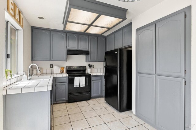 404 Mellowood Ct, Suisun City, CA 94585 - kitchen featuring black appliances, tile counters, under cabinet range hood, light tile patterned floors, and gray cabinetry