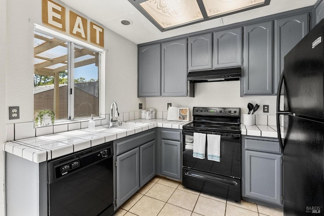 404 Mellowood Ct, Suisun City, CA 94585 - kitchen featuring black appliances, under cabinet range hood, light tile patterned flooring, and tile counters