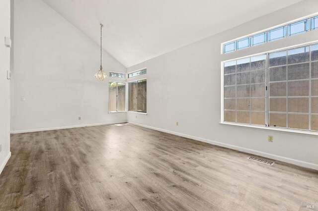 404 Mellowood Ct, Suisun City, CA 94585 - unfurnished dining area with a chandelier, high vaulted ceiling, healthy amount of natural light, and wood finished floors