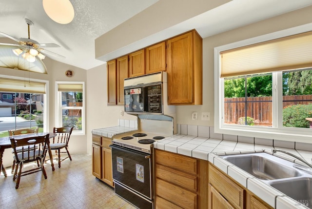 2340 Canton Ct, Fairfield, CA 94534 - kitchen with brown cabinets, lofted ceiling, ceiling fan, range with electric stovetop, and tile countertops