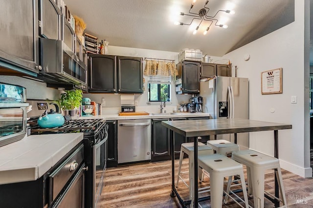 29 Pine Tree Cir, Cotati, CA 94931 - kitchen with stainless steel appliances, tile countertops, light wood finished floors, lofted ceiling, and a chandelier