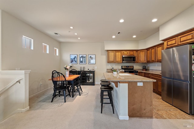 180 Healdsburg Ave Unit B, Cloverdale, CA 95425 - kitchen with appliances with stainless steel finishes, recessed lighting, brown cabinetry, a center island with sink, and a breakfast bar area