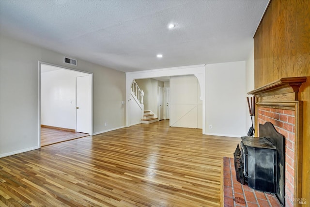8567 Davona Dr, Dublin, CA 94568 - unfurnished living room featuring stairway, light wood finished floors, a textured ceiling, a brick fireplace, and recessed lighting
