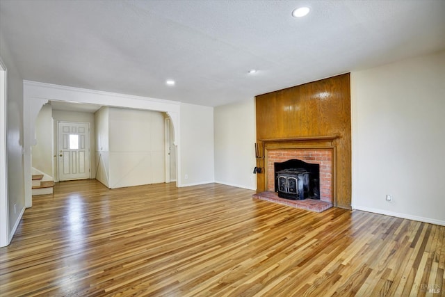 8567 Davona Dr, Dublin, CA 94568 - unfurnished living room featuring light wood-style floors, arched walkways, a wood stove, stairs, and recessed lighting