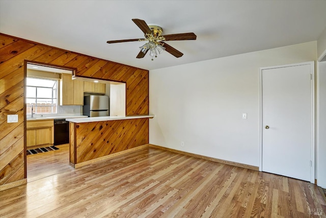 8567 Davona Dr, Dublin, CA 94568 - kitchen with freestanding refrigerator, black dishwasher, light countertops, wooden walls, and light wood-style flooring
