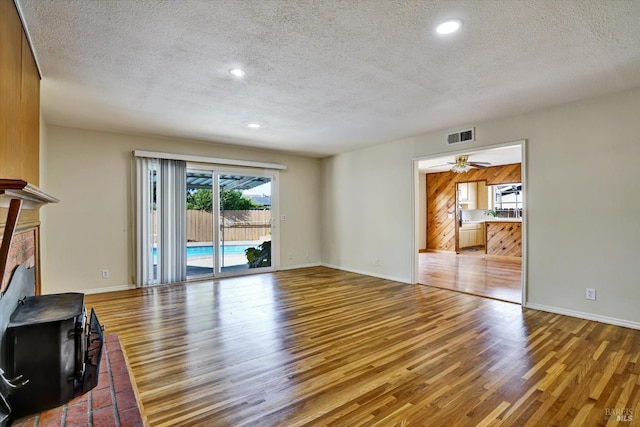 8567 Davona Dr, Dublin, CA 94568 - unfurnished living room with a textured ceiling, wood finished floors, recessed lighting, and a wood stove