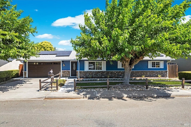 216 Walnut St, Suisun City, CA 94585 - view of front of house with stone siding, an attached garage, concrete driveway, roof mounted solar panels, and stucco siding