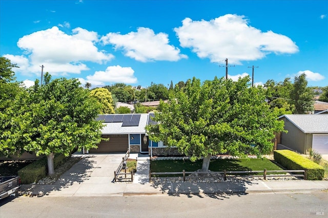 216 Walnut St, Suisun City, CA 94585 - obstructed view of property featuring a fenced front yard, solar panels, concrete driveway, a garage, and stone siding
