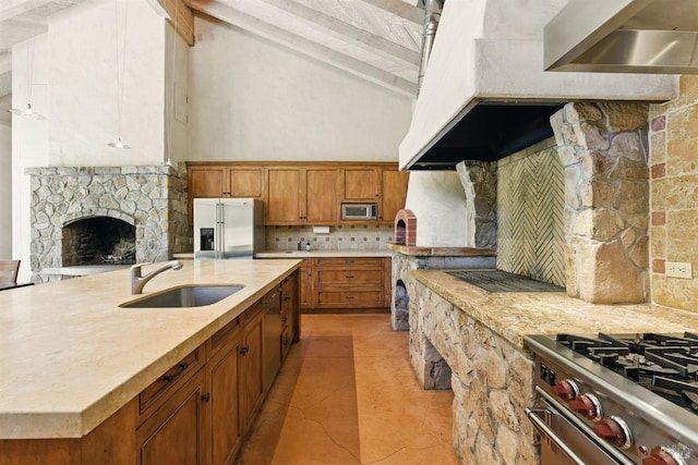 11018 Moonshine Rd, Sebastopol, CA 95472 - kitchen featuring appliances with stainless steel finishes, tasteful backsplash, brown cabinetry, a stone fireplace, and light tile patterned floors