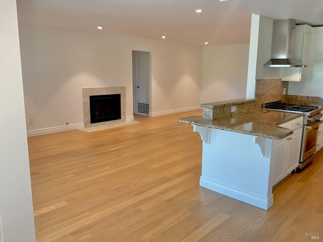 164 Oak Island Dr, Santa Rosa, CA 95409 - kitchen with high end stainless steel range oven, wall chimney range hood, a breakfast bar, a peninsula, and light wood finished floors