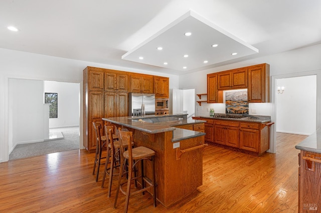 3604 Holly Ridge Dr, Santa Rosa, CA 95409 - kitchen with stainless steel appliances, brown cabinetry, dark countertops, light wood finished floors, and a breakfast bar area