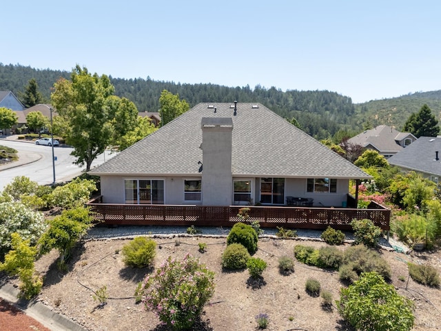 6327 Meadowridge Dr, Santa Rosa, CA 95409 - back of house with stucco siding, a chimney, a shingled roof, a view of trees, and a deck