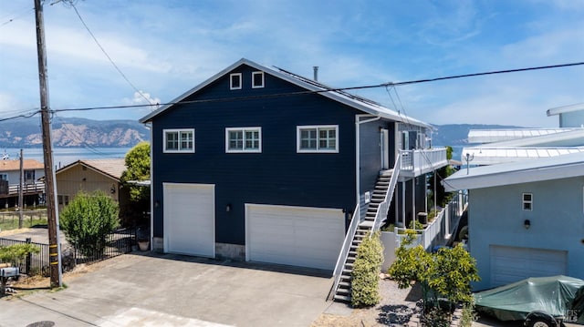 view of front of property featuring stairs, concrete driveway, a mountain view, and an attached garage
