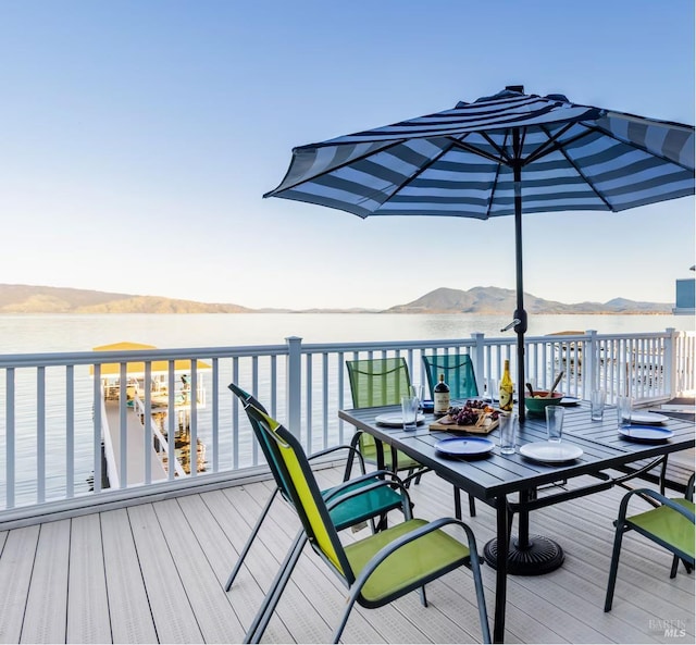 deck with a water and mountain view and outdoor dining area