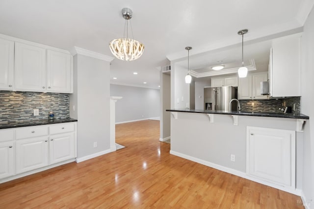 1255 Oak Ridge Ln, Pinole, CA 94564 - kitchen with stainless steel refrigerator with ice dispenser, backsplash, ornamental molding, white cabinetry, and a kitchen bar