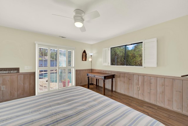 2588 King Edward Ct, El Dorado Hills, CA 95762 - bedroom with wainscoting, wooden walls, multiple windows, wood finished floors, and ceiling fan