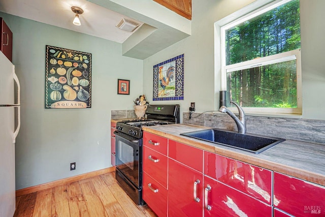 2685 Austin Creek Rd, Cazadero, CA 95421 - kitchen with red cabinetry, black gas range oven, freestanding refrigerator, and light wood finished floors