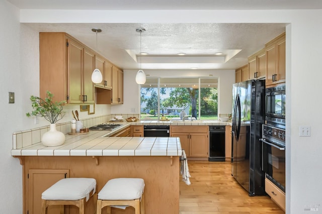 378 Miramonte Pl, Santa Rosa, CA 95409 - kitchen featuring black appliances, a raised ceiling, a peninsula, light wood-style flooring, and a kitchen bar