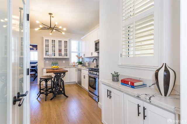 1 Hoffman Ave Unit A, San Francisco, CA 94114 - kitchen featuring appliances with stainless steel finishes, a chandelier, light wood finished floors, backsplash, and white cabinets