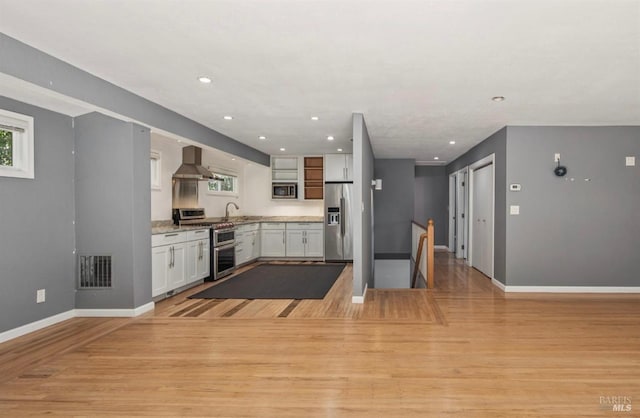 31 Buckelew St, Sausalito, CA 94965 - kitchen with appliances with stainless steel finishes, wall chimney exhaust hood, white cabinets, light wood-style flooring, and recessed lighting