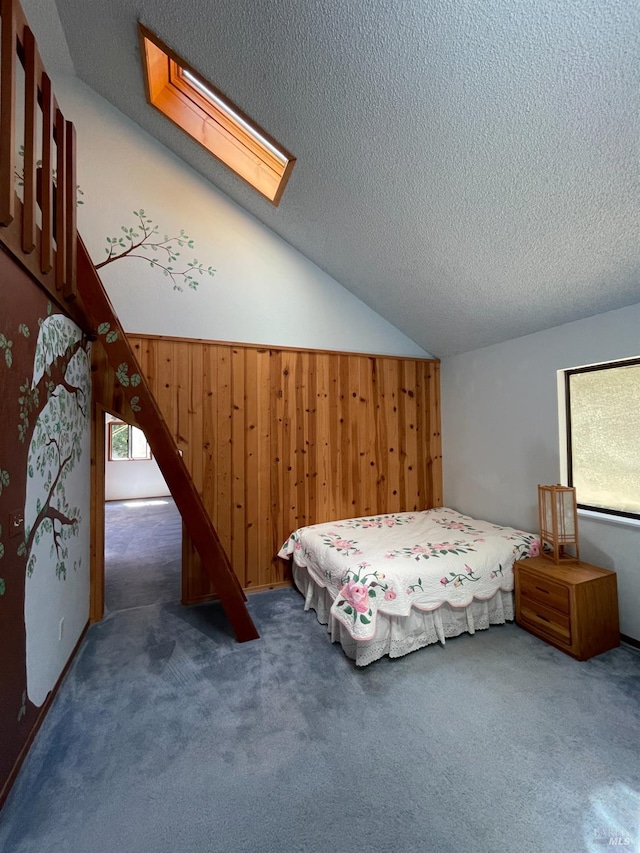 32691 Pearl Dr, Fort Bragg, CA 95437 - carpeted bedroom featuring wooden walls, a skylight, a textured ceiling, and vaulted ceiling
