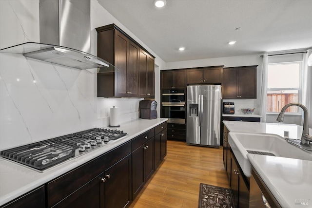 805 Broadfork Cir, Vacaville, CA 95687 - kitchen featuring appliances with stainless steel finishes, wall chimney range hood, dark brown cabinets, light wood-type flooring, and recessed lighting