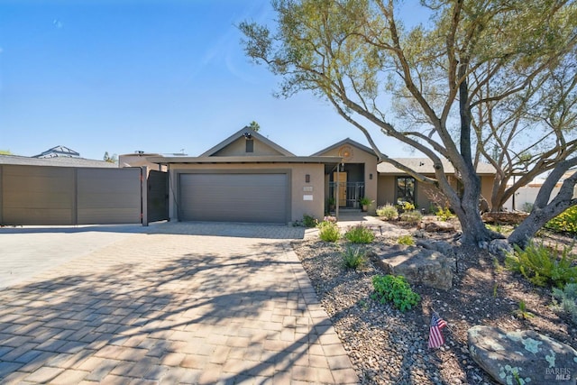 single story home with stucco siding, a garage, and decorative driveway