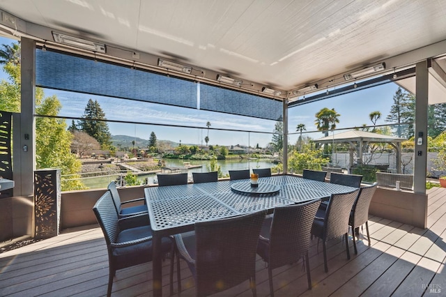 wooden terrace featuring a gazebo, a water view, and outdoor dining area