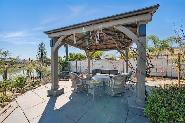 fenced backyard with a gazebo, a patio area, outdoor lounge area, a water view, and ceiling fan