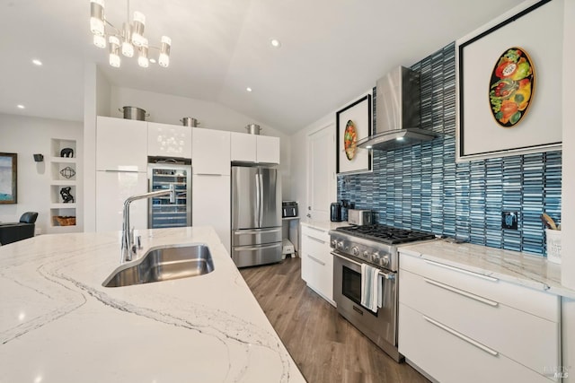 kitchen with stainless steel appliances, wall chimney range hood, beverage cooler, light wood finished floors, and vaulted ceiling