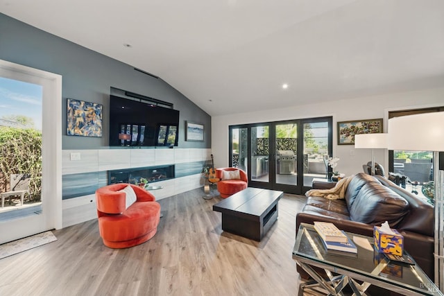 living area featuring lofted ceiling, wood finished floors, and french doors