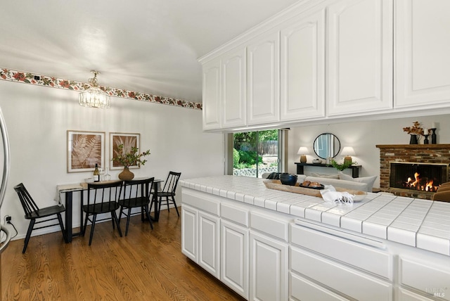 7 Arlene Ct, Petaluma, CA 94952 - kitchen featuring dark wood finished floors, tile counters, white cabinetry, a brick fireplace, and a chandelier