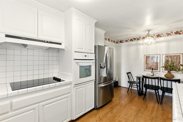 7 Arlene Ct, Petaluma, CA 94952 - kitchen featuring stainless steel fridge with ice dispenser, oven, under cabinet range hood, black electric cooktop, and tile countertops