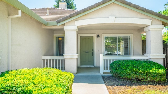 705 Wiegand Way, Dixon, CA 95620 - view of exterior entry with stucco siding, a chimney, a tiled roof, and covered porch