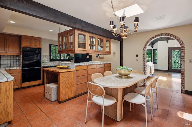 7 Shanley Ln, Ross, CA 94957 - kitchen with tile counters, backsplash, light tile patterned flooring, a chandelier, and arched walkways