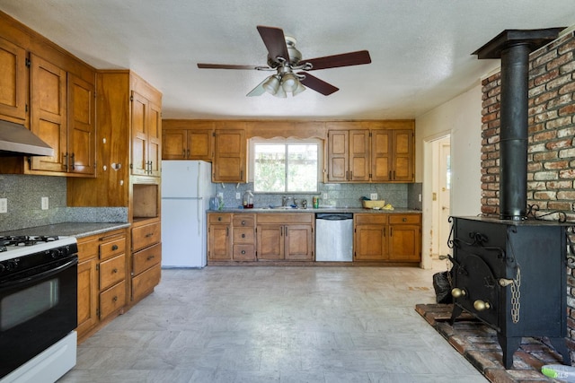 1415 Schaeffer Rd, Sebastopol, CA 95472 - kitchen featuring freestanding refrigerator, stainless steel dishwasher, range with gas stovetop, a wood stove, and brown cabinets