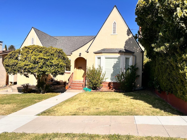 436 S Front St, Rio Vista, CA 94571 - tudor house featuring entry steps, roof with shingles, a front yard, and stucco siding