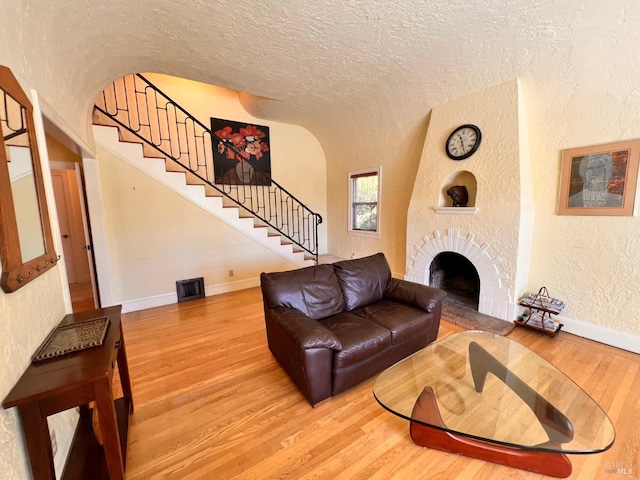 436 S Front St, Rio Vista, CA 94571 - living area featuring wood finished floors, stairs, a textured wall, a textured ceiling, and a fireplace