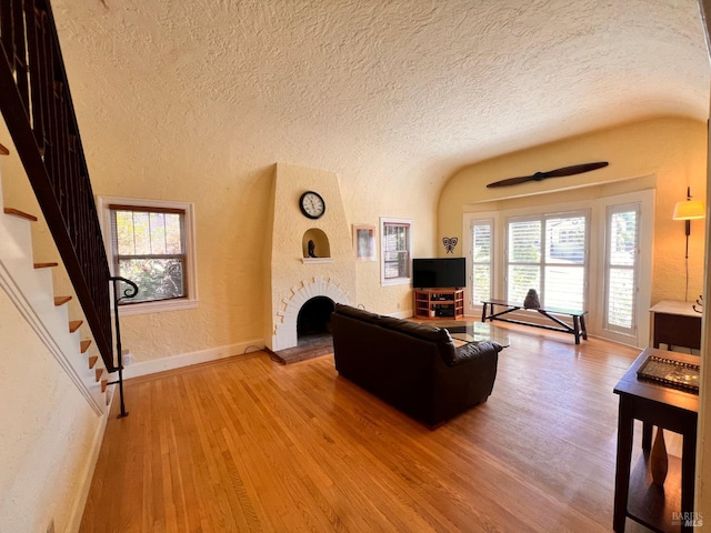 436 S Front St, Rio Vista, CA 94571 - living room featuring a textured wall, light wood-style floors, healthy amount of natural light, a textured ceiling, and a large fireplace