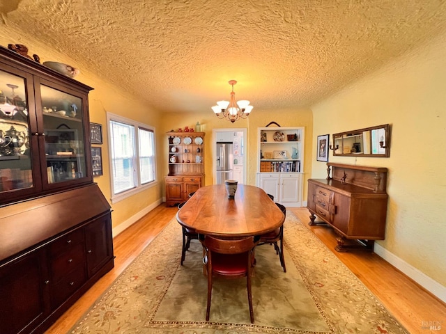 436 S Front St, Rio Vista, CA 94571 - dining room with a chandelier, light wood-style floors, built in shelves, and a textured ceiling