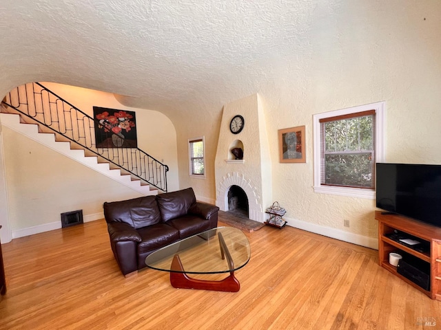 436 S Front St, Rio Vista, CA 94571 - living room with light wood finished floors, stairs, a textured ceiling, a textured wall, and a brick fireplace