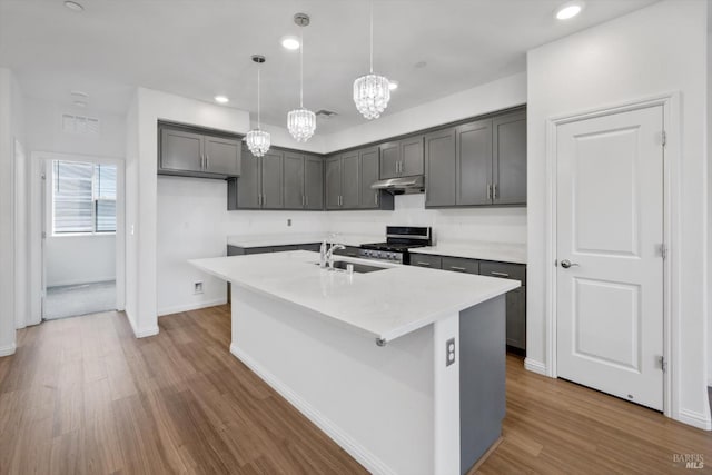 40708 Fremont Blvd, Fremont, CA 94538 - kitchen with under cabinet range hood, stainless steel range with gas cooktop, a chandelier, a center island with sink, and dark wood finished floors