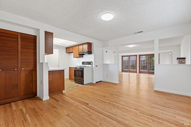 437 Ely Blvd S, Petaluma, CA 94954 - kitchen with gas range, under cabinet range hood, light wood-style flooring, a textured ceiling, and light countertops