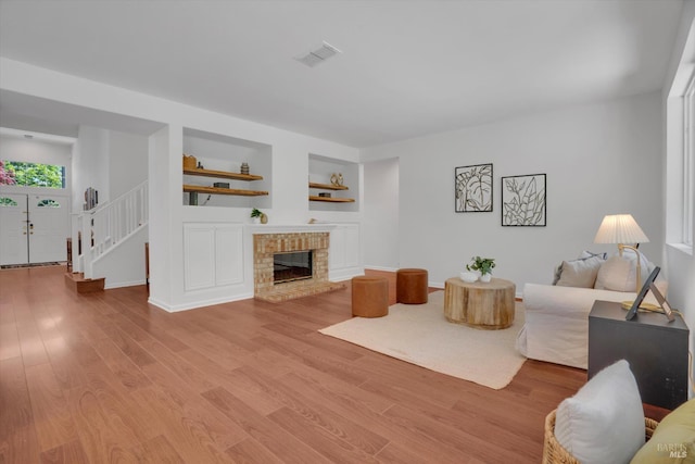 494 Mccall Dr, Benicia, CA 94510 - living room with stairway, built in shelves, light wood-style floors, and a brick fireplace