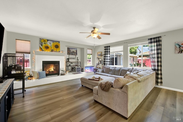 644 Canterbury Cir, Vacaville, CA 95687 - living area with a warm lit fireplace, ceiling fan, healthy amount of natural light, and wood finished floors