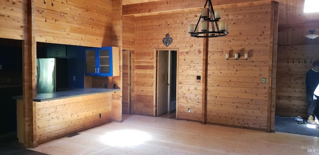 24663 Clover Rd, Willits, CA 95490 - unfurnished bedroom featuring wood walls, light wood-style flooring, freestanding refrigerator, and a chandelier