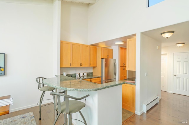 495 S Eliseo Dr Unit 7, Greenbrae, CA 94904 - kitchen with freestanding refrigerator, baseboard heating, a towering ceiling, light wood-style floors, and a breakfast bar